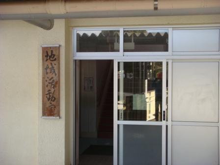 地域活動室と書かれた木製の表札が左にかかげられ、すぐ横に戸があり扉が開いている入り口の写真